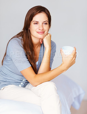 Thoughtful female drinking a cup of coffee at the bedroom