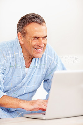 Cheerful elderly man surfing on a laptop against white