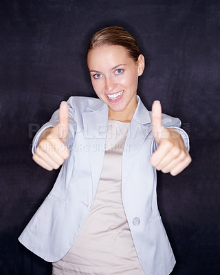 Smiling business woman gesturing a thumbs up against black